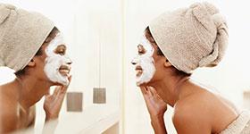  African American woman washing face looking in the mirror